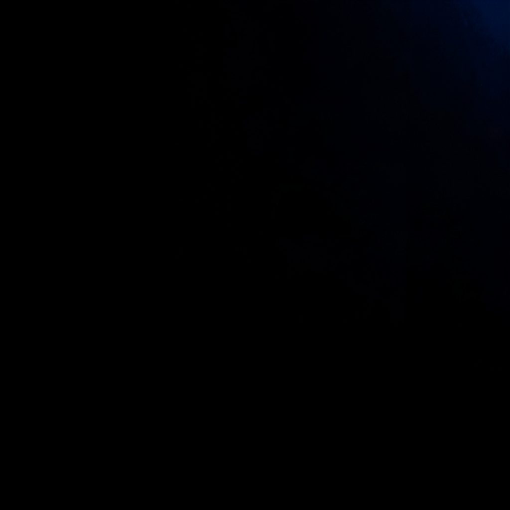Dark photograph of a laptop screen displaying a WordPress admin dashboard with plugin settings, deep shadows across the desk